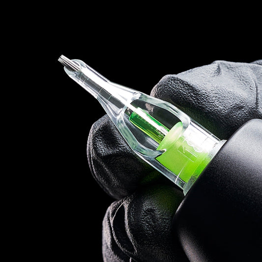 Black-gloved hand holding a clear tattoo needle cartridge with a lime green accent attached to a pen machine.