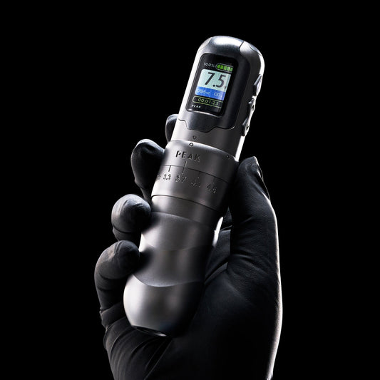Peak adjustable-stroke tattoo machine showing its stroke dial and digital voltage display.