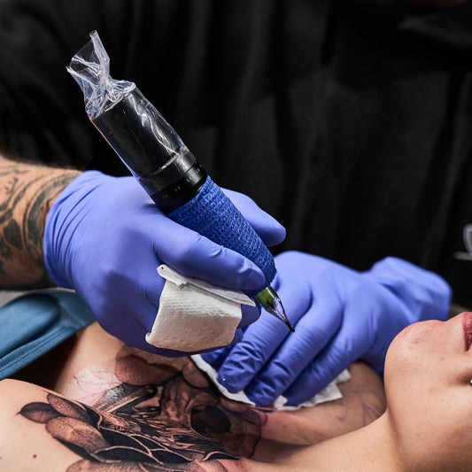 Artist using a battery-powered tattoo machine for chest shading.