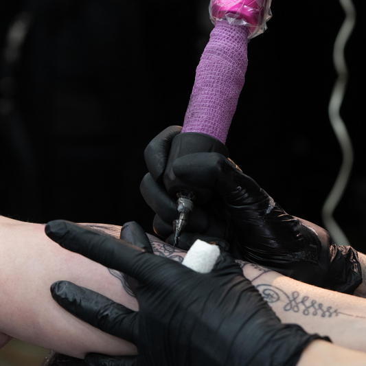 Artist in the groove, pushing limits on an intricate custom arm tattoo.