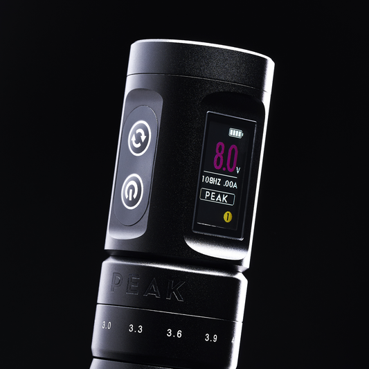 A close-up of a black Peak tattoo machine showing 8.0V and adjustable stroke settings on a digital display.